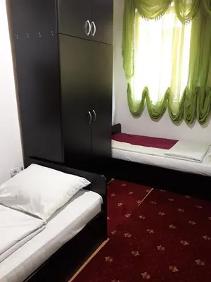 a bedroom with two beds and a window with green curtains at 