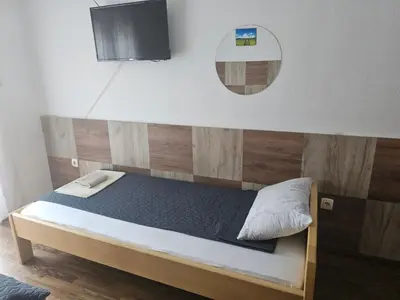 a bed with a wooden headboard and a mirror at Restoran i sobe 