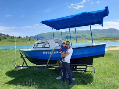 a man and a child standing in front of a boat at Mediteran B&B in Prozor