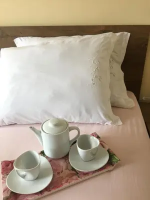 two cups and saucers on a bed with a pillow at Stan na dan Gradiška/Bos. Gradiška in Bosanska Gradiška