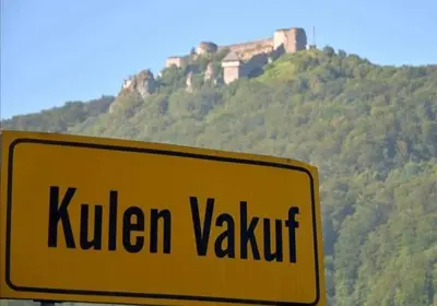a yellow sign in front of a hill with a castle at Naid Apartmani in Kulen Vakuf