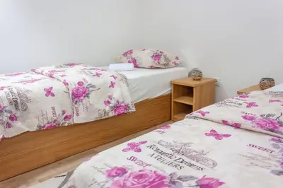 two beds in a room with pink flowers on them at Villa Maja in Bihać