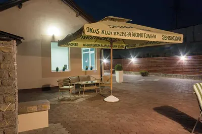 a patio with a table and an umbrella at night at Villa Maja in Bihać