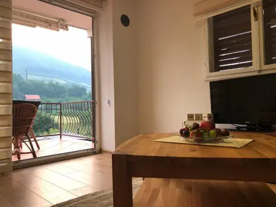 a living room with a table and a view of a balcony at Ammirevole -MOON- Apartment in Visoko