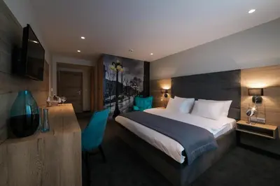 a hotel room with a large bed and a desk at Hotel Bank in Kiseljak