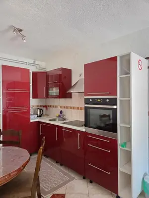 a kitchen with red cabinets and a sink and a table at Biser-Hatinac in Bihać