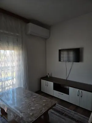 a living room with a table and a tv on the wall at Biser-Hatinac in Bihać