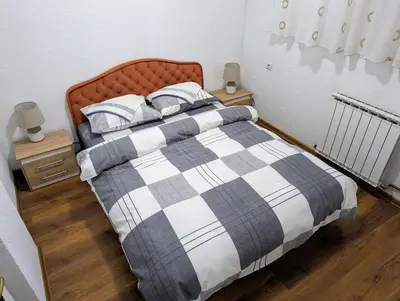 a bed with a checkered blanket and pillows at Apartment LAMI - Kalibunar, Travnik in Travnik