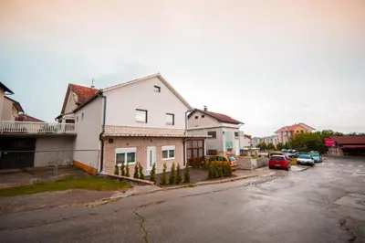 a white house with cars parked in a parking lot at Apartman Lucija in Livno