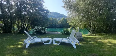 two white chairs sitting in the grass near a lake at Guest House VEZ Bihac in Bihać