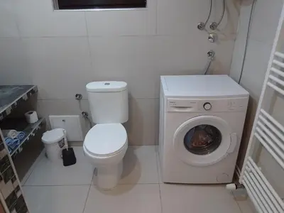 a bathroom with a toilet and a washing machine at Apartmani Natura in Sanski most