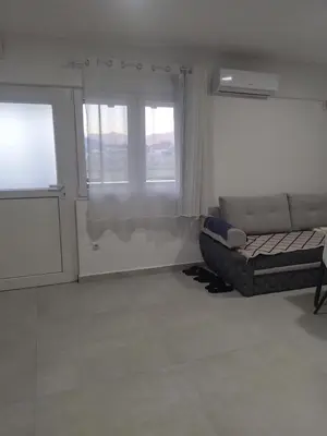 a living room with a couch and two windows at Apartmani Natura in Sanski most