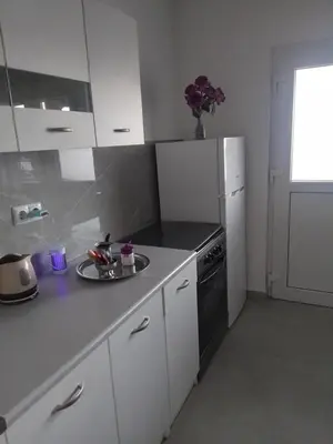 a kitchen with white cabinets and a white refrigerator at Apartmani Natura in Sanski most