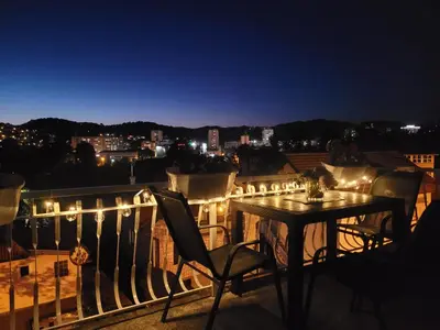 a table and chairs on a balcony at night at Apartmani ELEGANCE Tuzla in Tuzla