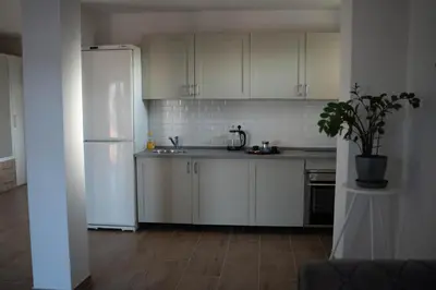 a kitchen with white cabinets and a white refrigerator at Apartmani ELEGANCE Tuzla in Tuzla