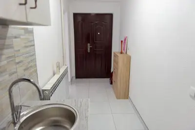 a bathroom with a sink and a brown door at Apartmani ELEGANCE Tuzla in Tuzla