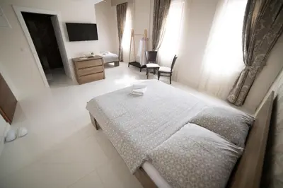 a bedroom with a bed and a chair and a television at Hotel Urban in Bužim