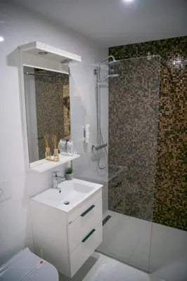 a white bathroom with a shower and a sink at Hotel Urban in Bužim