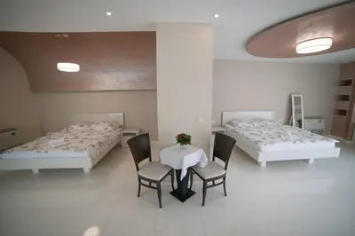 a room with two beds and a table and chairs at Hotel Urban in Bužim
