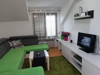 a living room with a green couch and a tv at Receptiva BL in Banja Luka