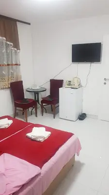a room with a bed and chairs and a television at Prenociste Sana Sanski Most in Sanski most
