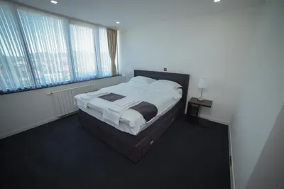a bedroom with a bed and two windows at Motel Grand in Velika Kladuša