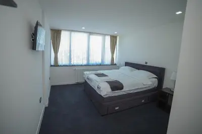 a bedroom with a bed and two windows at Motel Grand in Velika Kladuša
