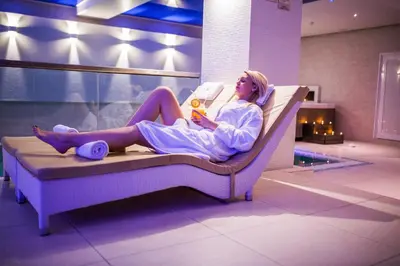 a woman sitting on a bed in a room at Hotel Park Doboj in Doboj