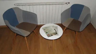 two chairs sitting next to a table with a magazine at Apartment Galerija in Tuzla