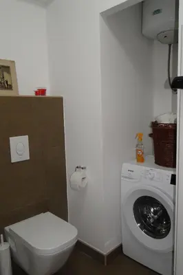a bathroom with a toilet and a washing machine at Apartment Galerija in Tuzla