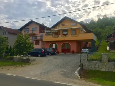 a house with cars parked in a parking lot at Apartman AS in Bihać
