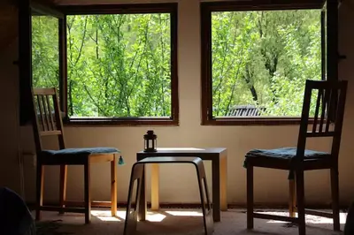 two chairs and a table in a room with two windows at Una holiday house in Bihać