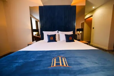 a hotel room with a large bed with a blue blanket at Hotel Ideja in Banja Luka