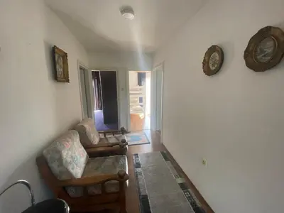 a living room with a chair and a clock on the wall at Vila Una 1 in Ripač