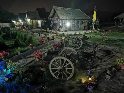 a garden with two wagon wheels in front of a house at Etno selo EDEN in Žeravački Potok