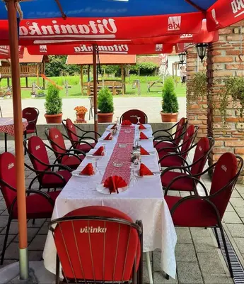 a long table with red chairs and a red umbrella at Etno selo EDEN in Žeravački Potok