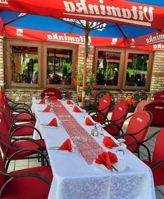 a long table with red chairs and a red umbrella at Etno selo EDEN in Žeravački Potok