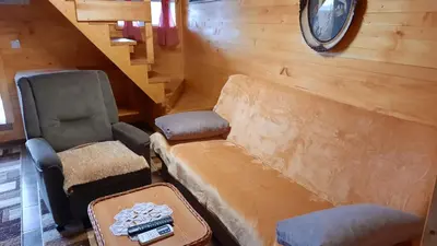 a living room with a couch and chairs and a clock at Etno selo EDEN in Žeravački Potok