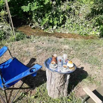a table on a tree stump with a blue chair at Cottage Forest Stream in Visoko
