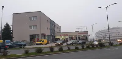 a street with cars parked in front of a building at Trosoban stan u Zenici in Zenica
