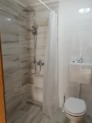 a bathroom with a shower with a toilet and a shower curtain at Vacation House Studenac in Bihać