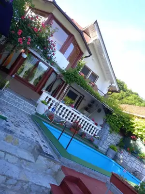 a house with a balcony and a blue pool at Villa Dino in Kulen Vakuf