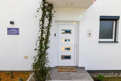 a white door with ivy climbing up the side of a house at simply-una in Bihać
