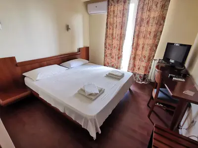 a bedroom with a bed and a desk and a television at Hotel Athos in Modriča