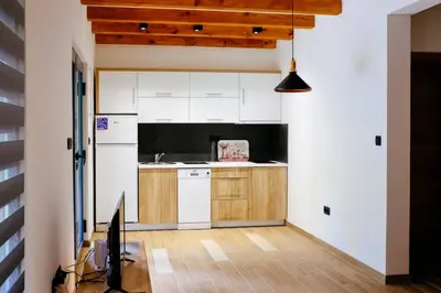 a kitchen with white cabinets and a wooden floor at Holiday home Green coast in Bosanska Krupa