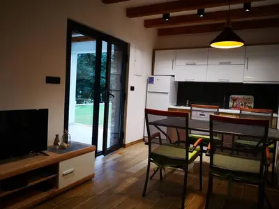 a kitchen with a table and chairs and a television at Holiday home Green coast in Bosanska Krupa