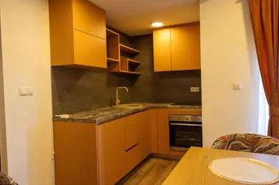 a kitchen with yellow cabinets and a wooden table at Apartments and Rooms Villa Majestic in Bihać