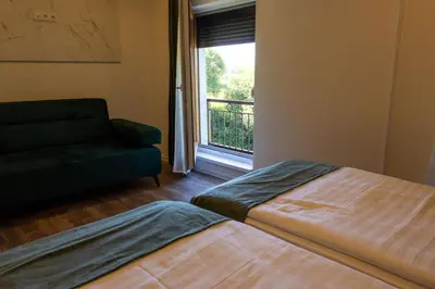 a bedroom with a bed and a couch and a window at Apartments and Rooms Villa Majestic in Bihać