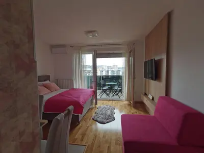 a bedroom with a pink bed and a couch at Apartman Krasula Doboj in Doboj