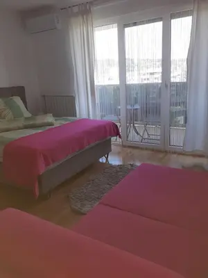 a bedroom with two beds and a large window at Apartman Krasula Doboj in Doboj